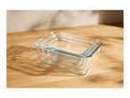 Set of three nested rectangular glass food storage containers on a wooden surface.