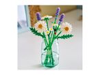 A bouquet of artificial daisies and lavender in a clear glass vase on a white surface.