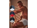 Un uomo in boxer grigi, con tre campioni circolari di tessuti per intimo con diversi motivi.