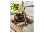 A person emptying a vacuum cleaner's dustbin into a kitchen sink.