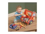 A young boy playing with a wooden toy car repair set, including a car, tools, and a jump start battery.