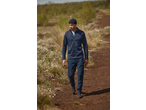 Man in blauw fleecejack, cargobroek en muts loopt op een zandpad.