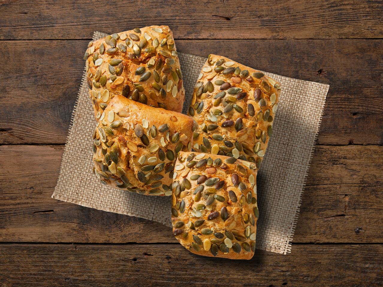 Vier Kürbiskernbrötchen auf Backpapier.