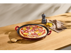 Assadeira de pizza de ferro fundido SILVERCREST com pizza, moedor de pimenta e guardanapo numa mesa de madeira.
