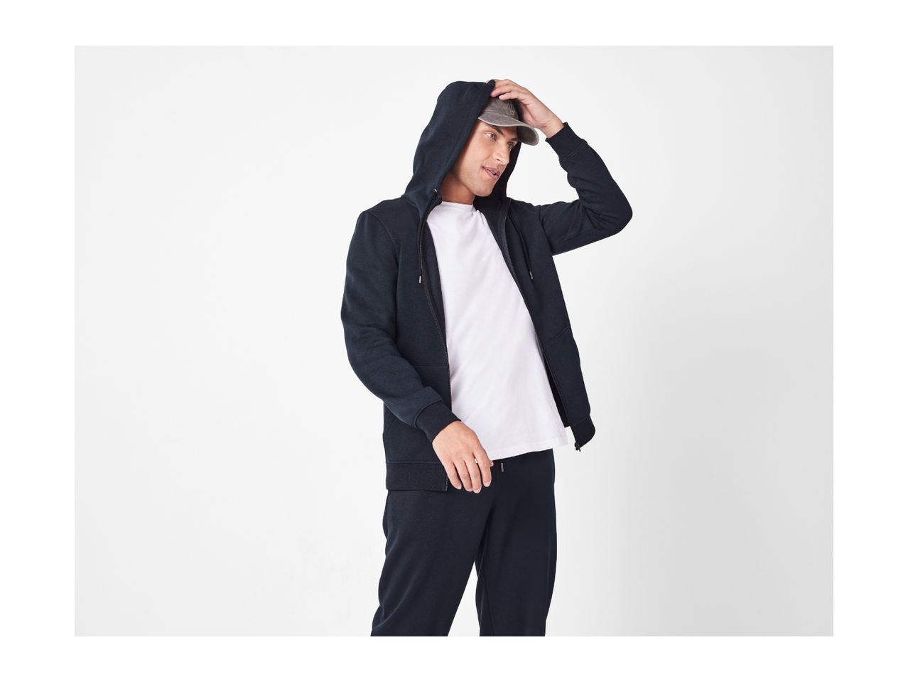 Man in a navy blue zip-up hoodie, white t-shirt, and navy blue joggers.