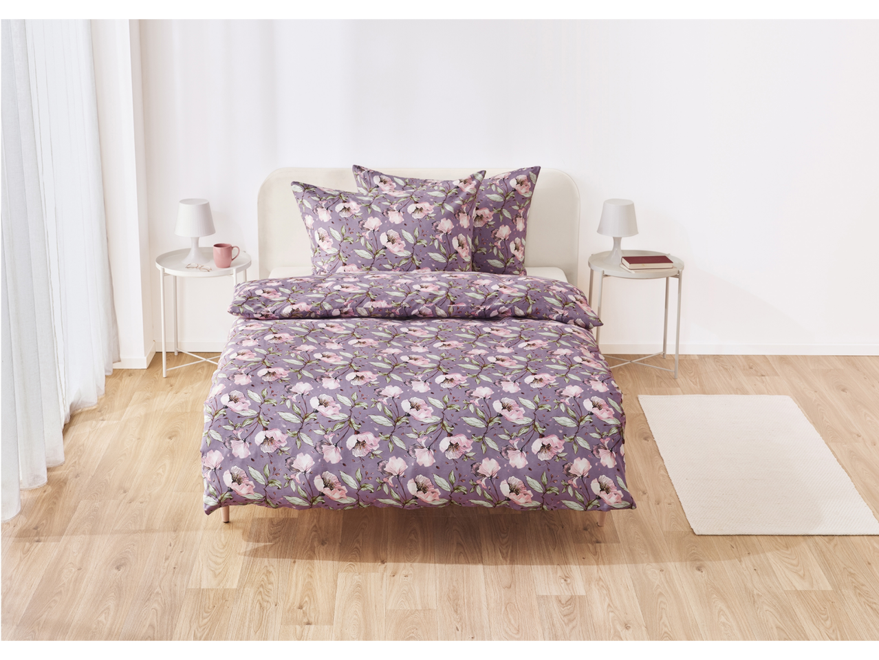 Lilac floral duvet cover set on a bed, with matching pillowcases.