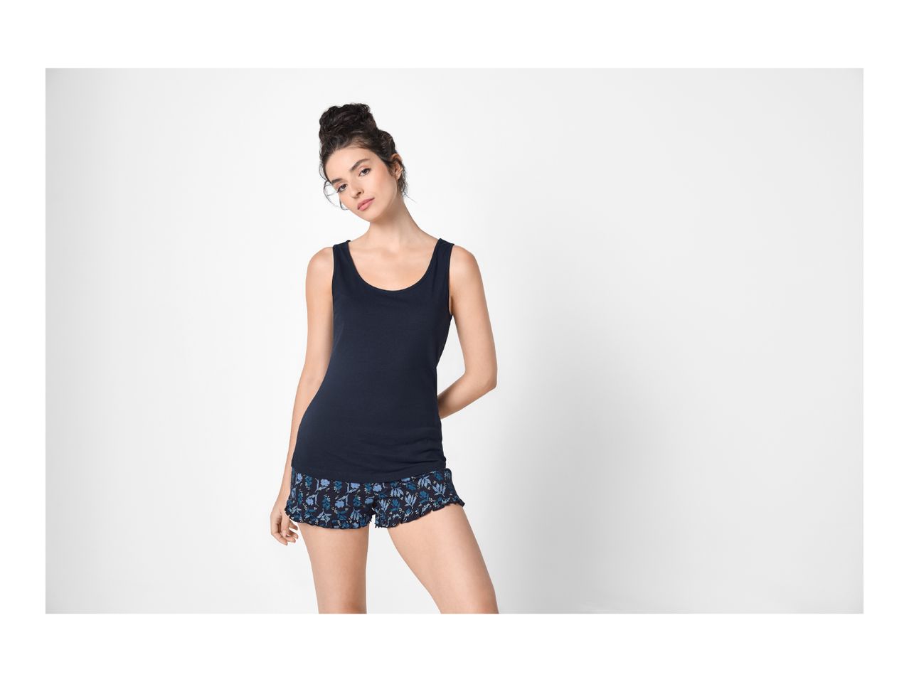 Woman in a navy blue tank top and floral print shorts.