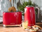 Red 1973 branded toaster and kettle on a kitchen counter with breakfast items.