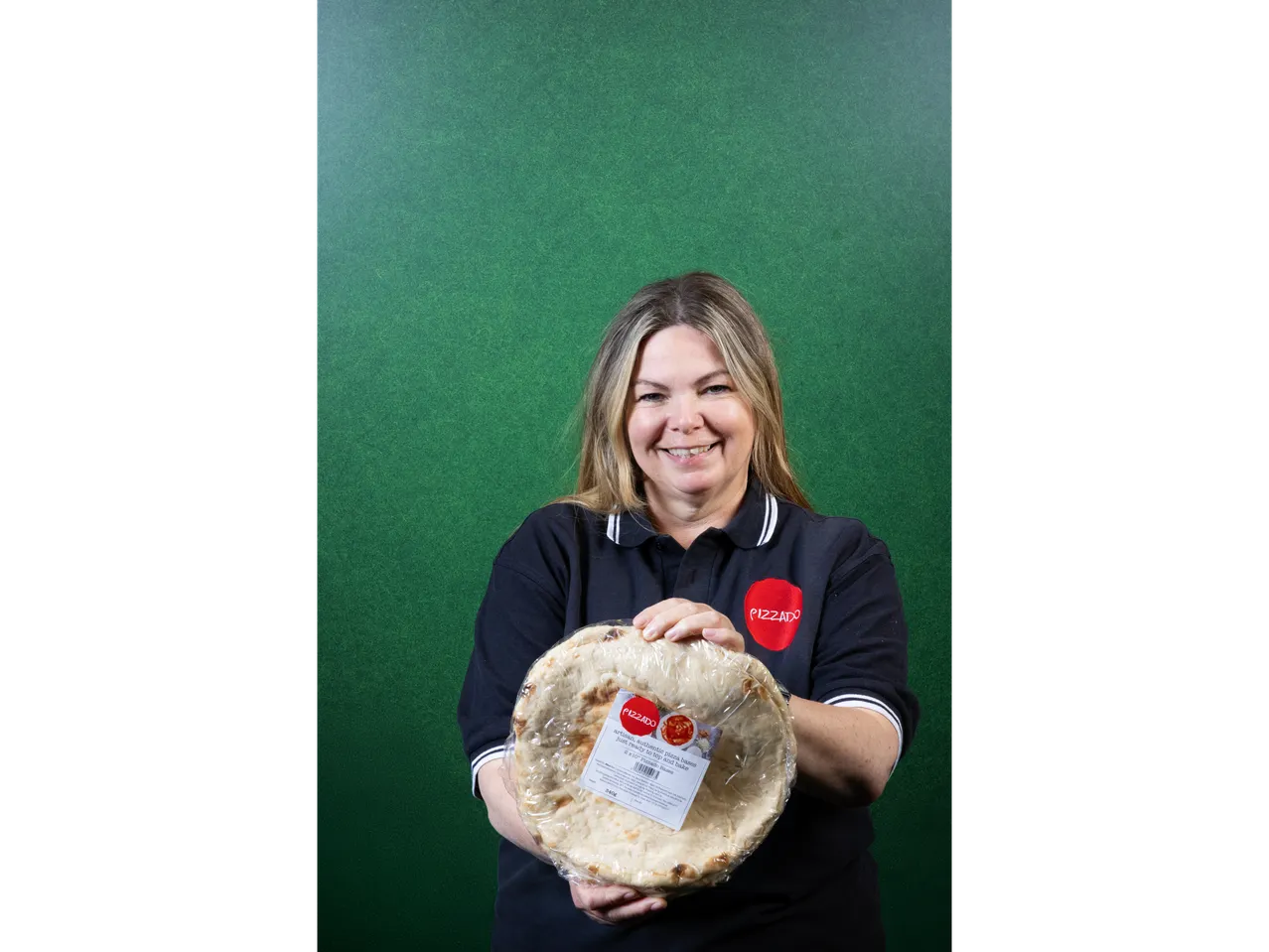 A woman holding two packaged pizza bases.