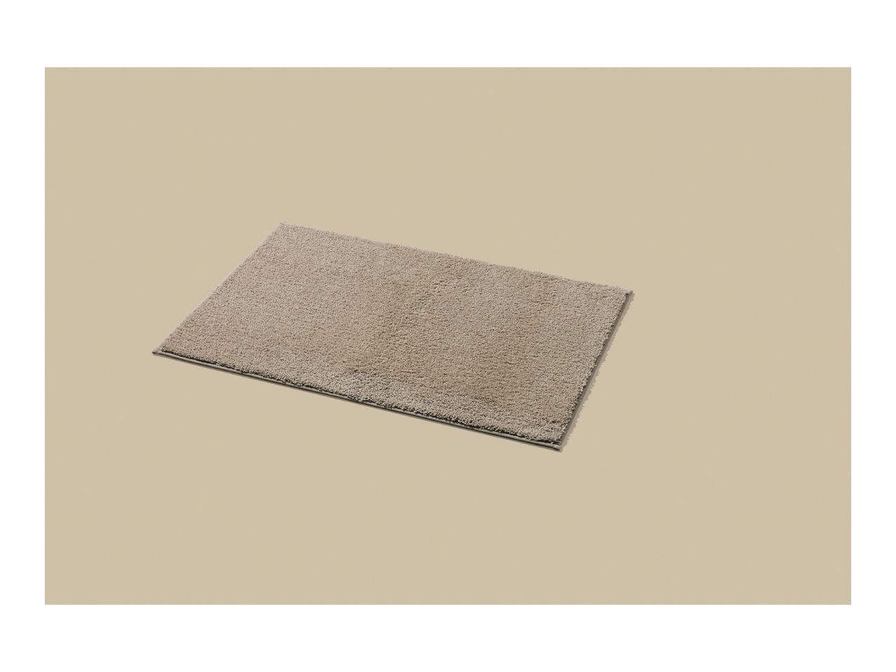 A rectangular beige bath mat with a shaggy texture on a light beige background.