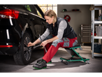 Žena u garaži mijenja automobilsku gumu s ključem za kotače.