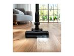 Cordless stick vacuum cleaner with LED lights on a wooden floor, cleaning dirt.