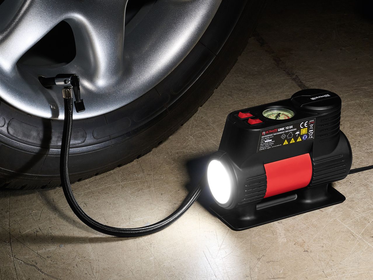 Ultimate Speed® мини компресор за гуми, свързан към автомобилна гума.