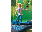 Menino de t-shirt cinzenta e calças de pijama azuis com personagens de desenhos animados, a saltar sobre roupa de cama azul.