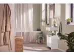 Casa de banho moderna com tapete de banho LIVARNO, banheira e lavatório brancos, e plantas verdes.