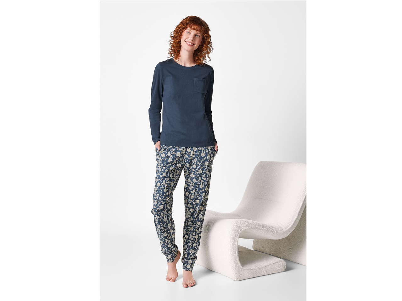 Femeie zâmbitoare în pijamale Esmara® cu bluză albastră și pantaloni cu model floral