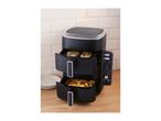 Black dual-basket air fryer with chicken and fries, on a wooden counter with white tiles.