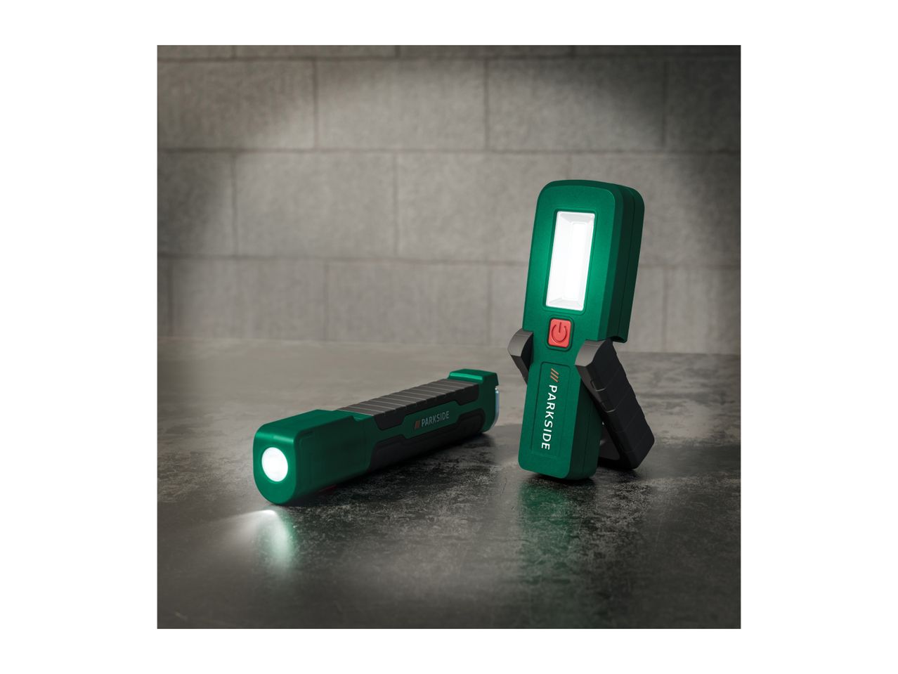 Two green and black Parkside work lights on a concrete surface.