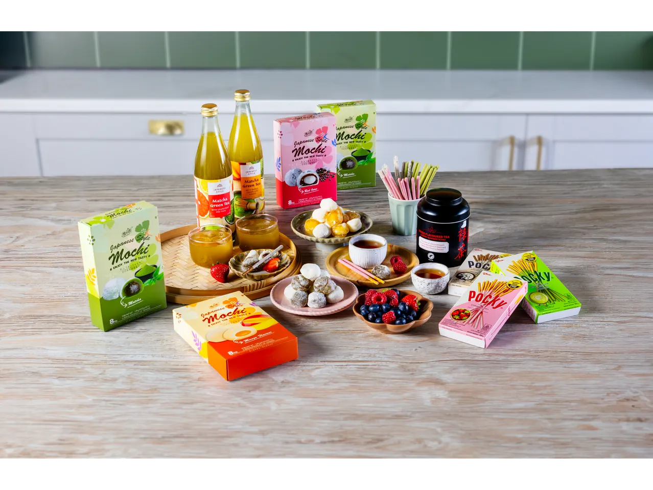 Japanese-style mochi, matcha green tea drinks, and Pocky sticks on a wooden table.