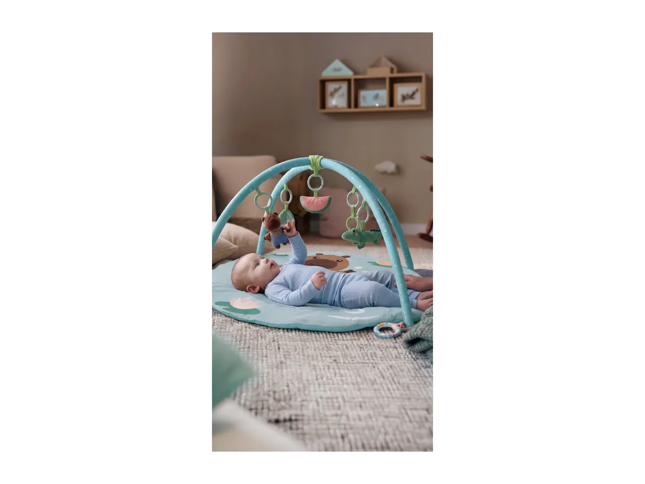 Baby on a playmat with an activity arch and hanging toys.