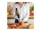 Woman blending tomato soup with an immersion blender in a kitchen setting.