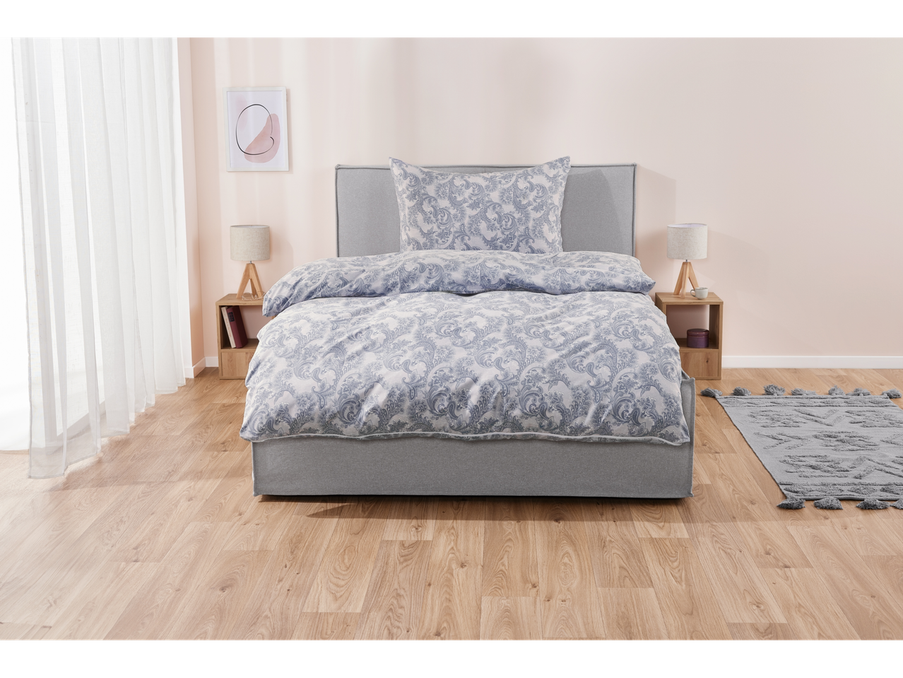 Grey upholstered bed with blue paisley bedding set.