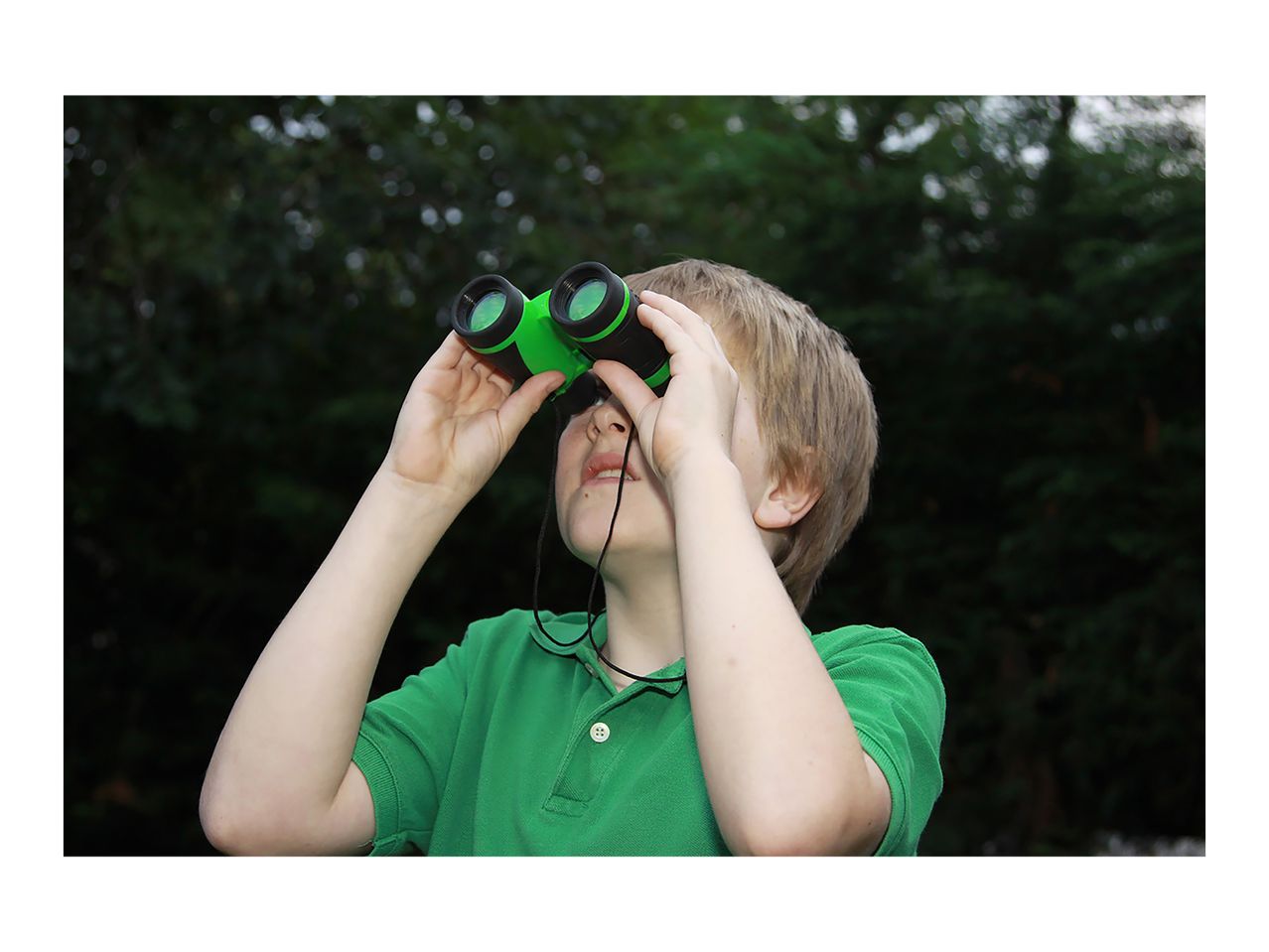 Child in green shirt looking up through green binoculars.
