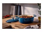 Blue enameled cast iron Dutch oven filled with stew, on a wooden countertop.