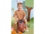 Um menino feliz brinca em um cavalinho de brinquedo em um cenário divertido.