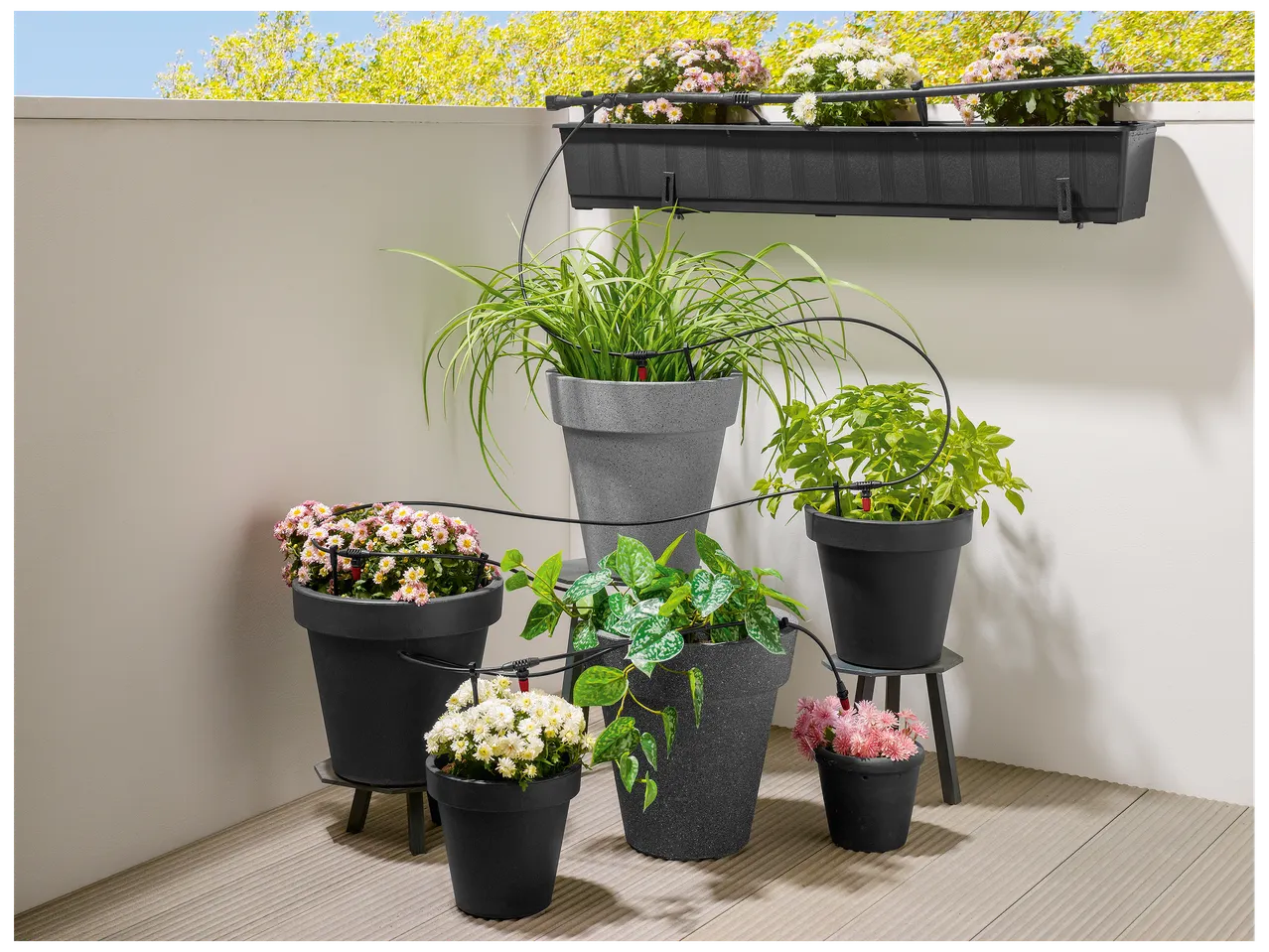 Balcon avec jardinières et pots de fleurs, équipés d'un système d'arrosage goutte-à-goutte.