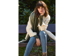 Woman in esmara® corduroy overshirt, green top, jeans, and scarf on a bench.