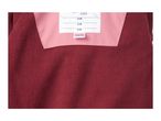 Close-up of a red fleece garment with a pink inner lining and a white label.