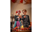 Two children in skeleton costumes and face paint, celebrating Halloween.