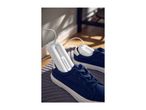 Electric shoe dryers inserted into a pair of blue canvas sneakers on a grey mat.