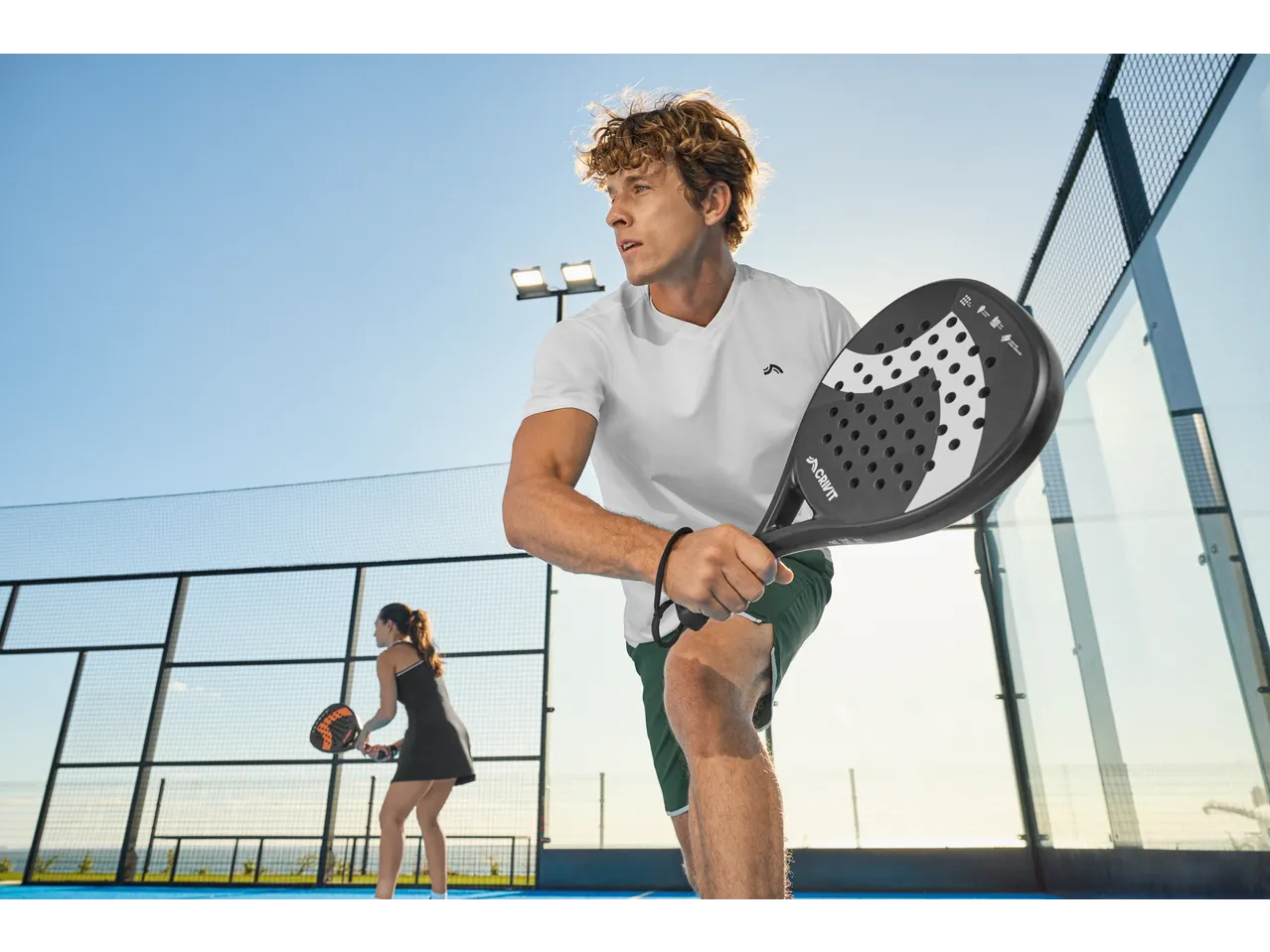 Padelspelers met CRIVIT rackets op een zonnige buitenbaan.