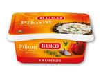 To pakker flødeost med løg og krydderurter, den øverste med et billede af ost på brød.