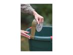 Person applying brown duct tape to the rim of a green bucket outdoors.