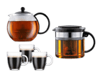 Zwei Teekannen und drei Kaffeetassen auf schwarzem Hintergrund.
