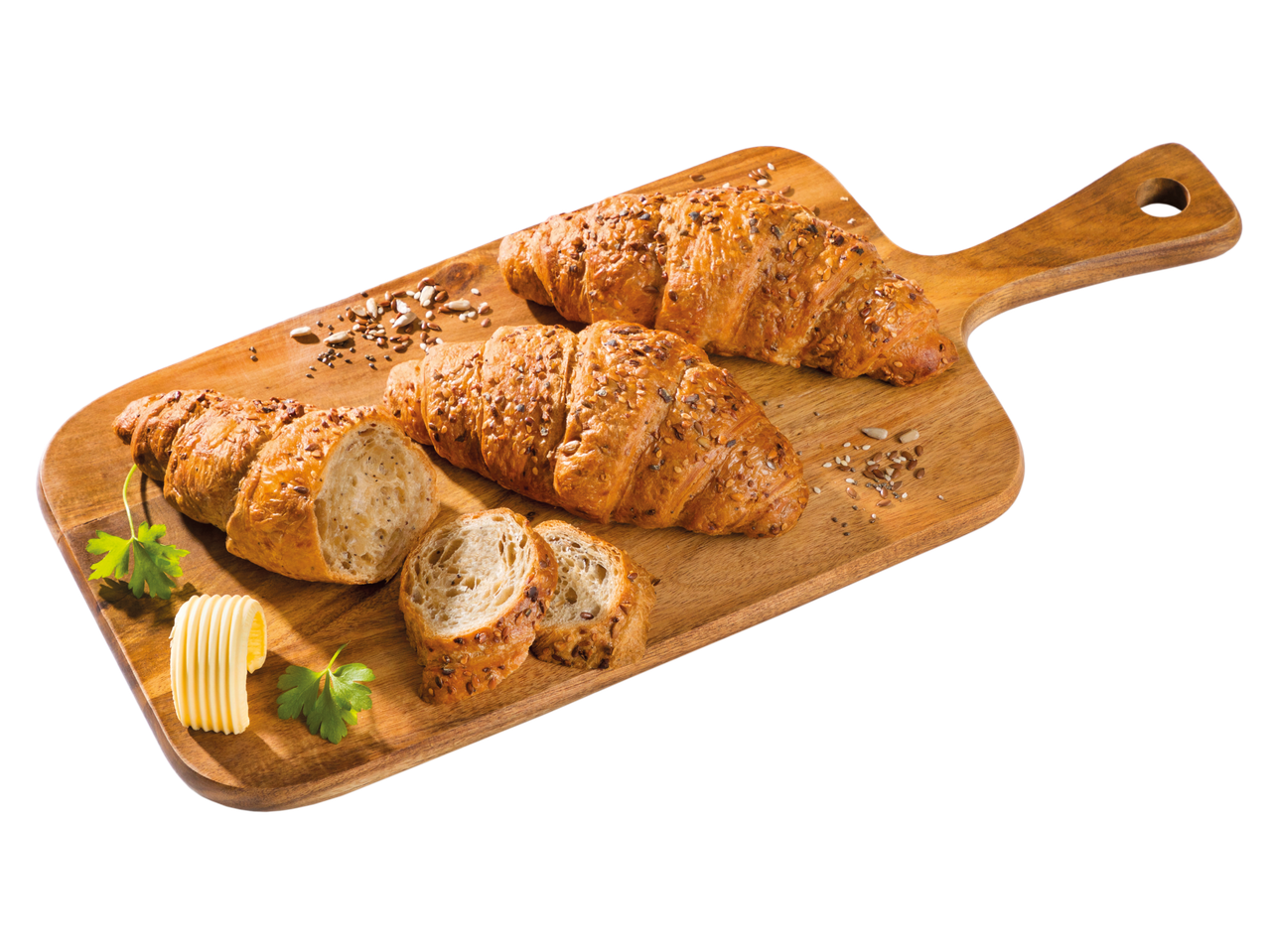 Croissanty se semínky a máslo na dřevěné prkénku.