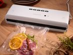 Silvercrest vacuum sealer with meat, orange slices, and herbs in a vacuum bag.