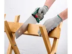 Un bărbat folosește un ferăstrău de mână Parkside® pentru a tăia o scândură de lemn.