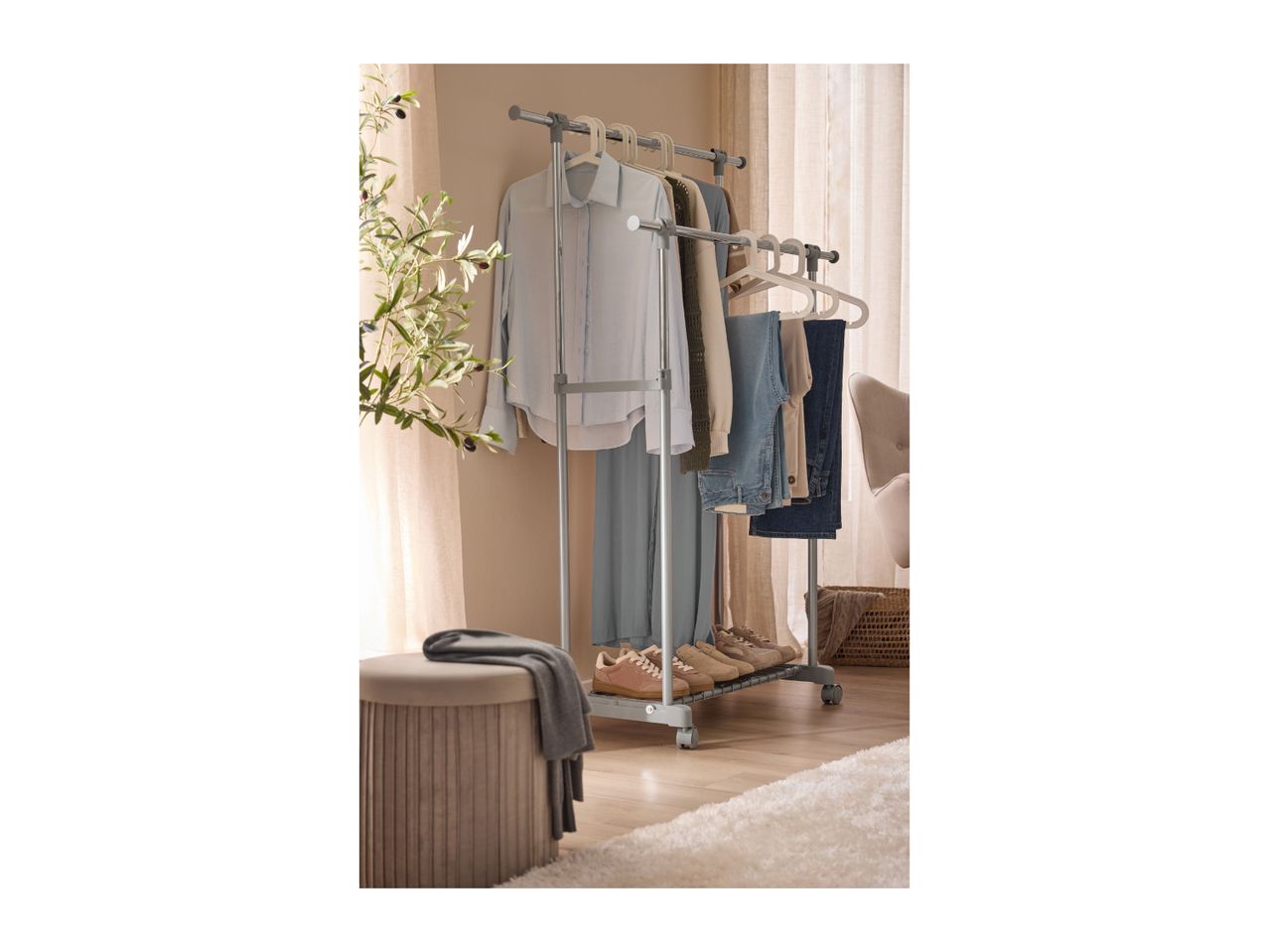 Clothes rack with shirts, trousers, and shoes, next to a plant and a stool.