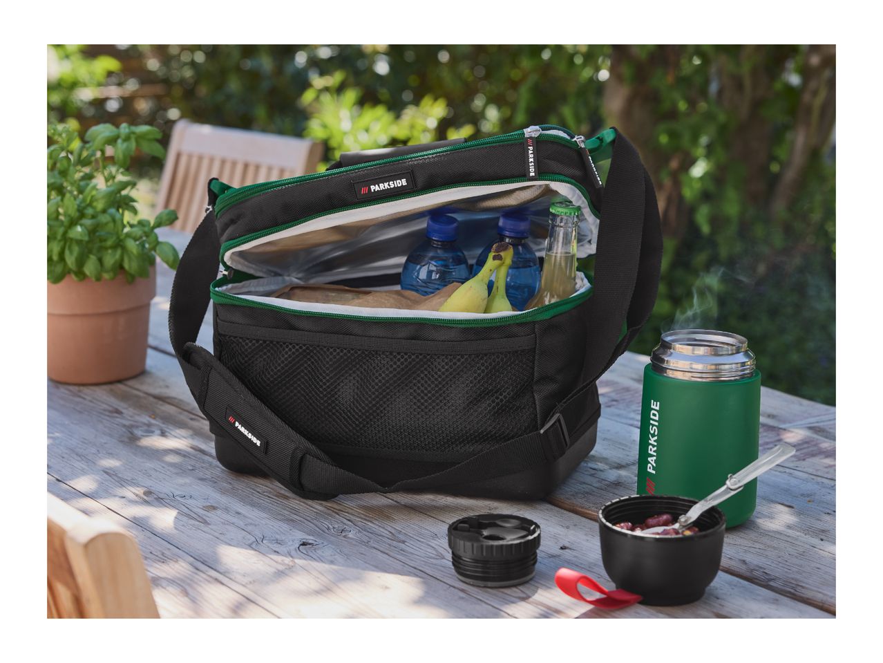 Parkside cooler bag with drinks and food, next to a Parkside thermos on a wooden table.