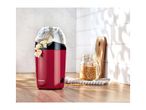 Red popcorn maker with popped corn, unpopped kernels in a jar on a wooden counter.