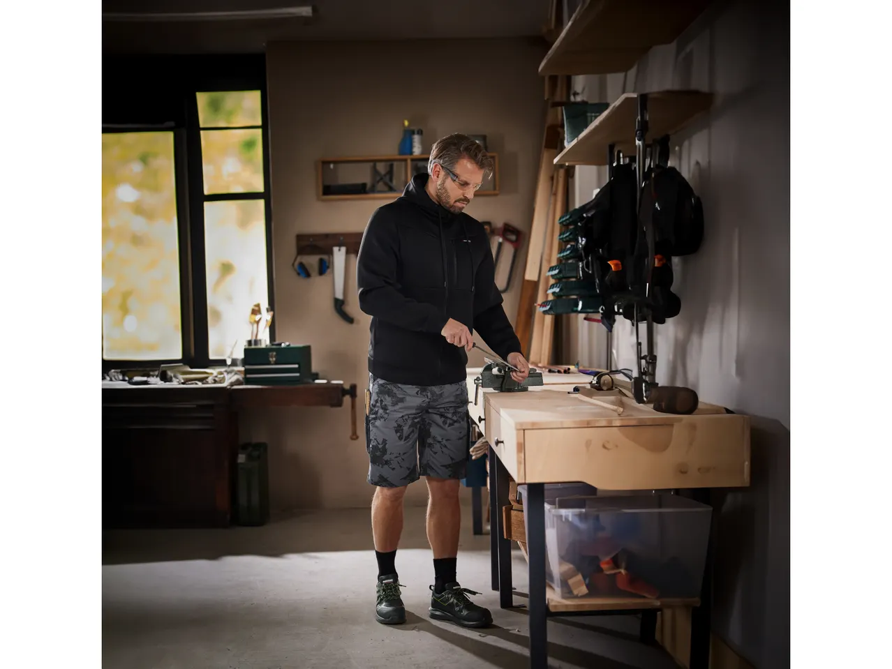 Un uomo indossa pantaloni corti e scarpe antinfortunistiche Parkside mentre lavora in un laboratorio.