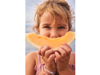 Smiling child holding a slice of fresh melon, enjoying a healthy snack.