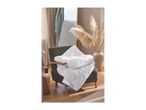 White quilted duvet on a green armchair in a cozy living room with pampas grass.