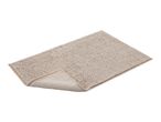 A rectangular beige bath mat with a textured, looped surface, partially folded to show the underside.