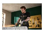 Man using an angle grinder, sparks flying, in a workshop setting.