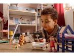A child plays with a Lupilu wooden doll's house and various doll figures and furniture.